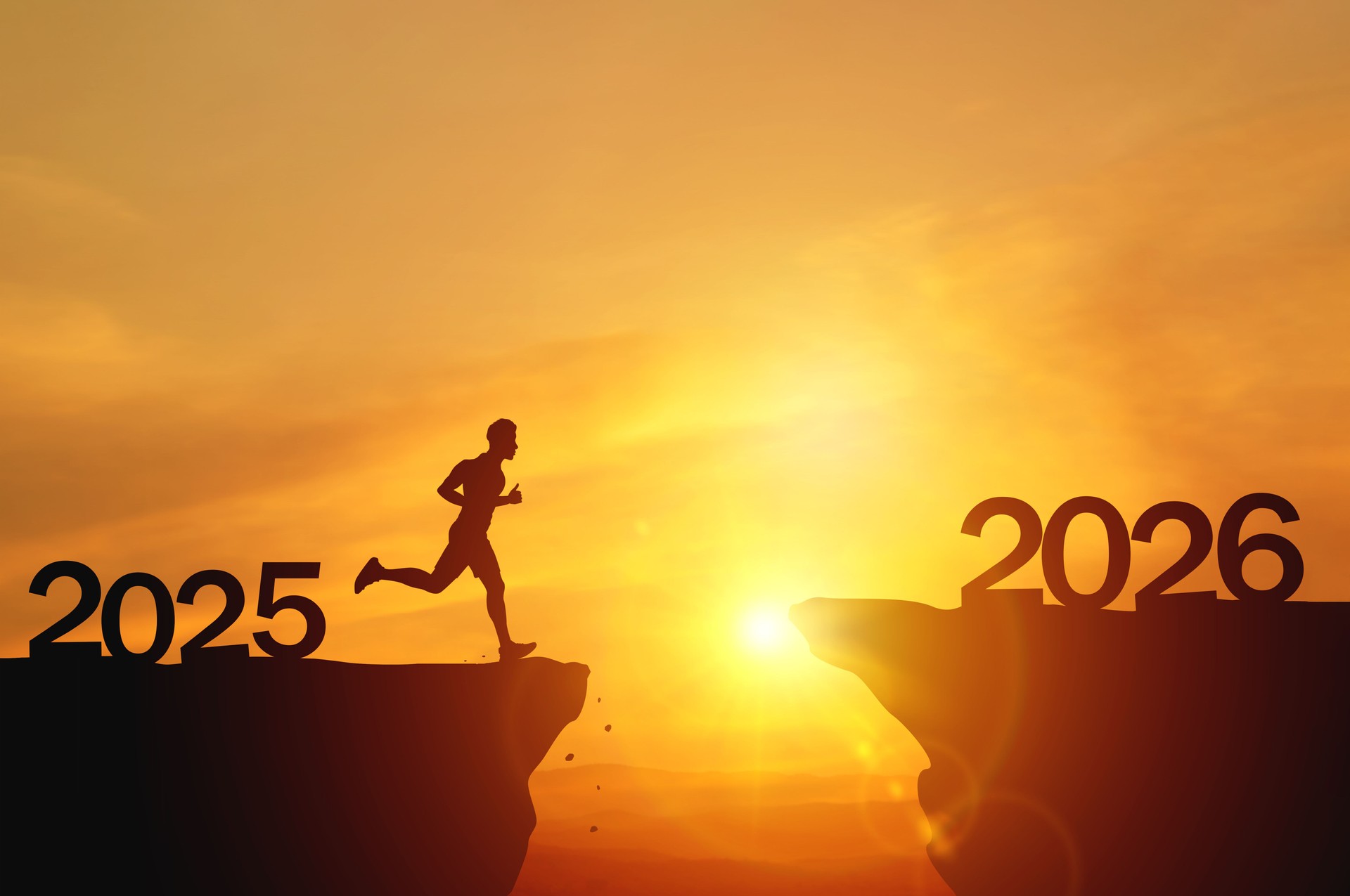 New Year 2026, Inspiration and progress towards new success. Silhouettes of human jumping over cliff towards finish line on sunset beautiful
