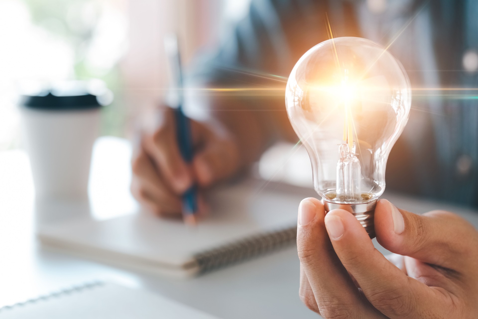 Innovation through ideas and inspiration ideas. Human hand holding light bulb to illuminate, idea of creativity and inspiration concept of sustainable business development.